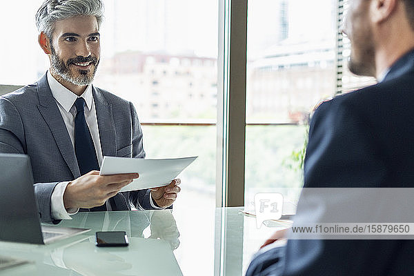 Smiling businessman holding document in office