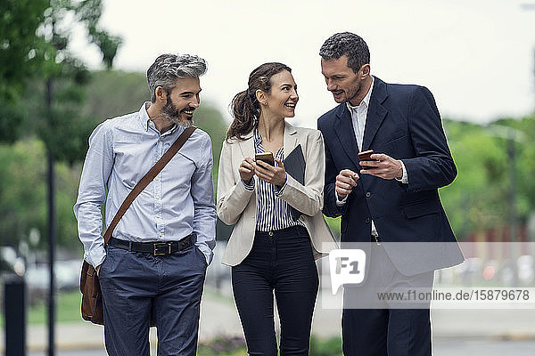 Geschäftsleute benutzen Smartphones in einem öffentlichen Park