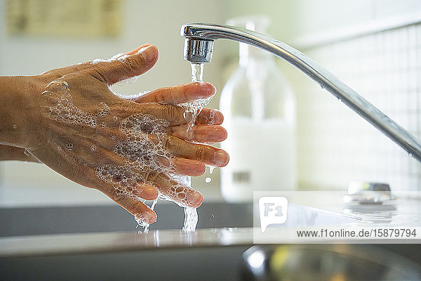 Mann wäscht Hände mit Seife im Waschbecken