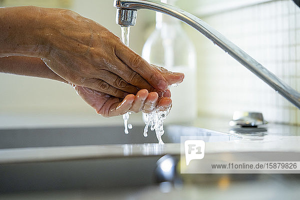 Man washing hands with water in bathroom sink