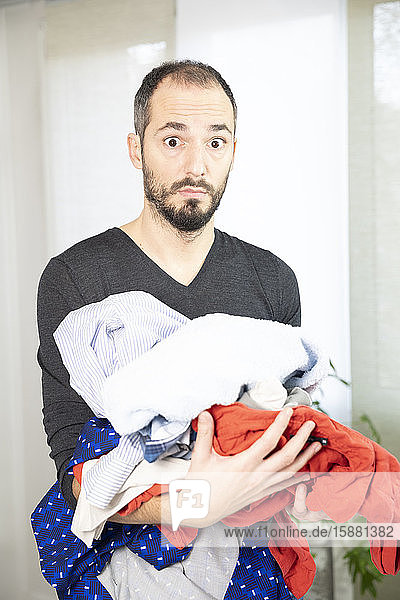 A man terrified by ironing  sorting washing.