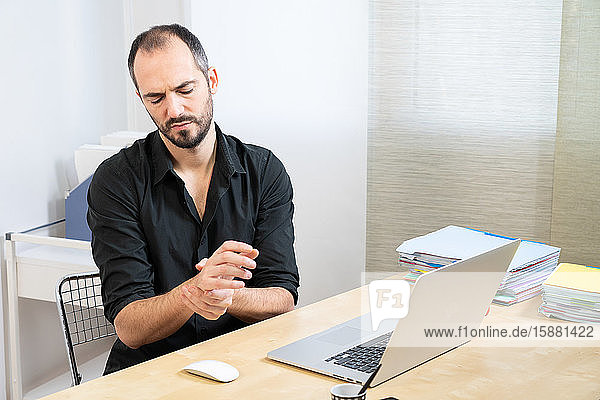A man at his desk with hand pain.