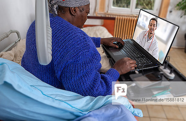 Die Geschäftsfrau macht während ihres Krankenhausaufenthalts zu Hause weiter ihre Hausaufgaben. Im Bett bleiben und Internet-Konsultation mit ihrem Arzt führen
