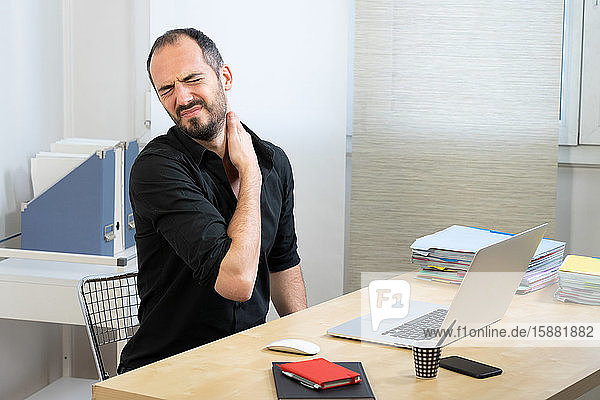 A man at his desk with neck pain.