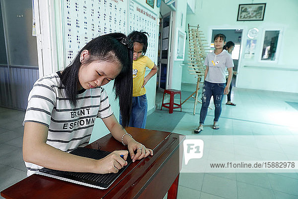 Center for blind children run by Children Action. Girl writing braille. Ho Chi Minh city. Vietnam.