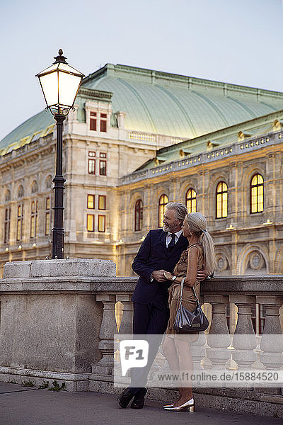 Ein Paar  das am frühen Abend in Wien Arm in Arm an einer Balustrade lehnte.