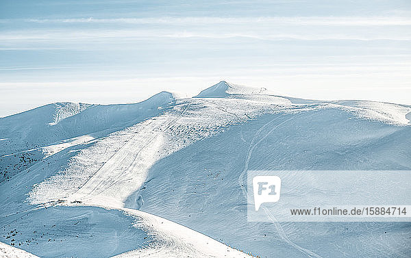 Blick auf menschenleere Skipisten in den Bergen leere Pisten mit Schneespuren.