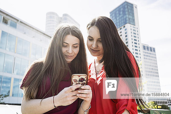 Two women standing in a Berlin street looking at a mobile phone.