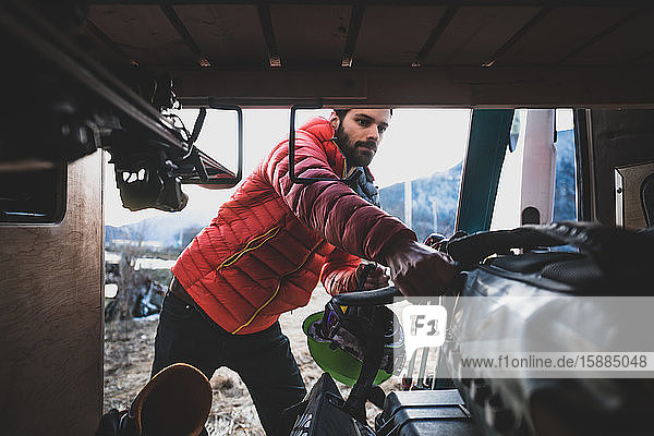 Man reaching into a van to take out skiing equipment.