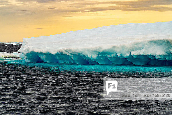 Close up of a glacier on the Antarctic sea blue underneath and white above.