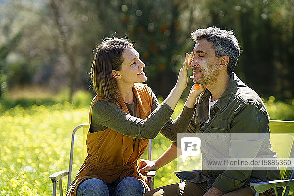 Young woman putting sunscreen on her boyfriend in the field