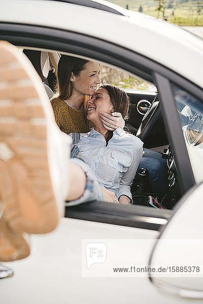 Zwei glückliche  liebevolle junge Frauen in einem Auto