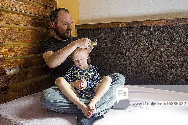 Vater bindet seiner kleinen Tochter die Haare