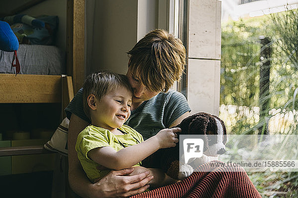Mother and little son cuddling near window