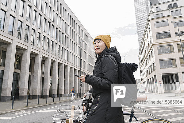 Frau mit Fahrrad und Smartphone in der Stadt  Frankfurt  Deutschland