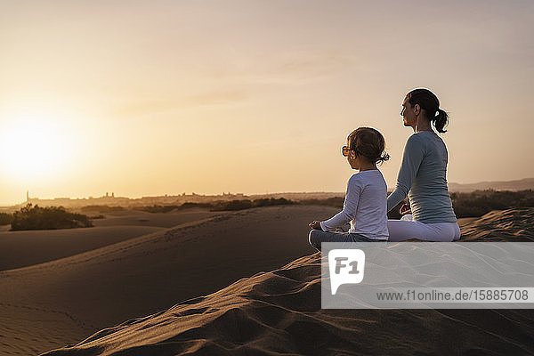 Mutter und Tochter praktizieren Yoga in Sanddünen bei Sonnenuntergang  Gran Canaria  Spanien