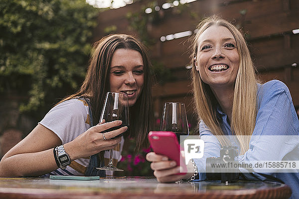 Portrait of two happy women having a glass of red wine outdoors