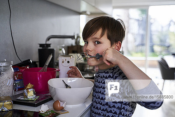 Portrait of boy tasting batter in kitchen