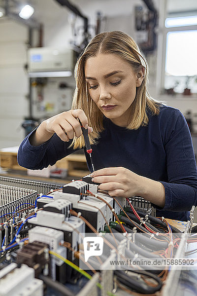 Female electrician working on circuitry in workshop