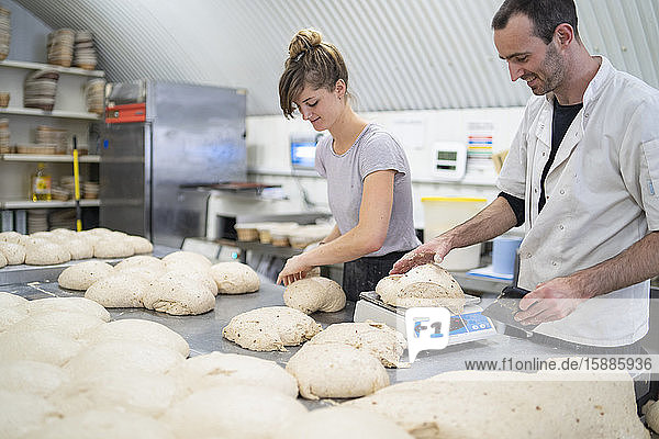 Mann und Frau bereiten in einer Bäckerei Brotlaibe zu