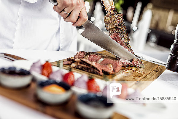 Hands of chef slicing tomahawk steak