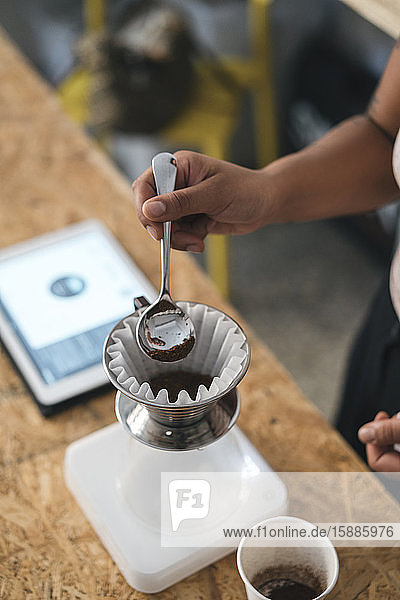 Nahaufnahme einer Frau  die in einer Kaffeerösterei arbeitet und frischen Filterkaffee zubereitet