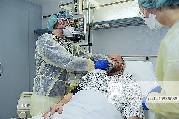 Ärzte  die Patienten auf der Notfallstation eines Krankenhauses mit Beatmungsgeräten versorgen