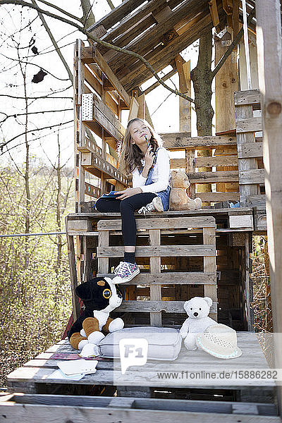 Nachdenkliches Mädchen spielt mit ihren Teddybären im Baumhaus