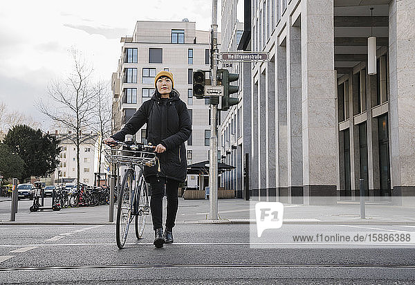 Woman with bicycle in the city on the go  Frankfurt  Germany