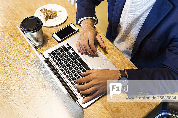 Crop view of businessman working on laptop in a coffee shop