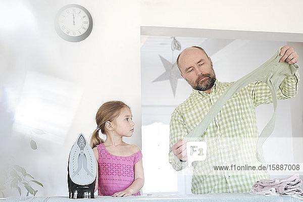 Father and daughter ironing together at home