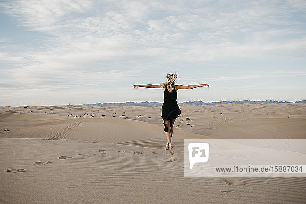 Rückenansicht einer blonden Frau  die in die Luft springt  Algodones Dunes  Brawley  USA