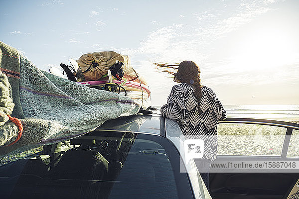 Rückenansicht einer Frau mit Auto am Strand mit Blick auf das Meer  Tafedna  Marokko