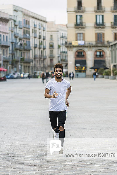 Portrait of laughing young man running on a square  Barcelona  Spain