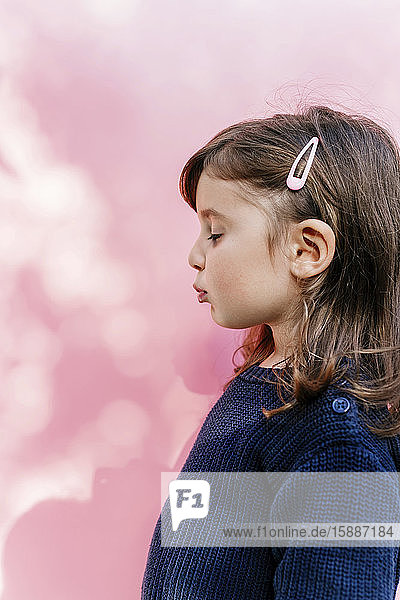 Profil eines kleinen Mädchens mit geschlossenen Augen vor rosa Hintergrund