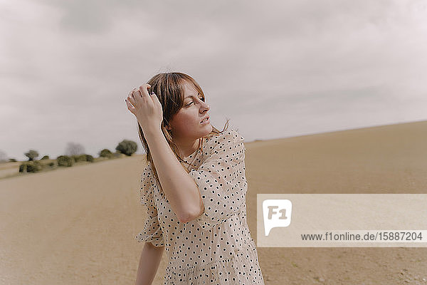 Frau in Vintage-Kleid allein auf einem abgelegenen Feld auf dem Land