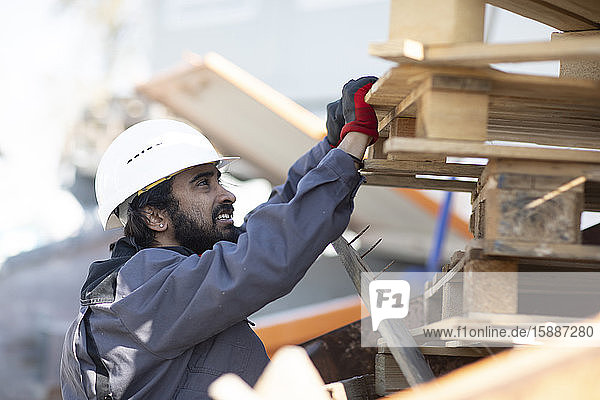 Techniker mit Helm und Bart prüft Holzpaletten