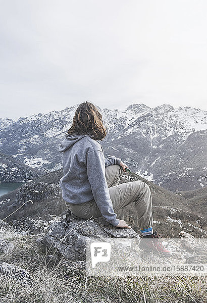 Rückenansicht einer jungen Frau  die auf einem Felsen sitzt und auf die Aussicht schaut  Provinz León  Spanien