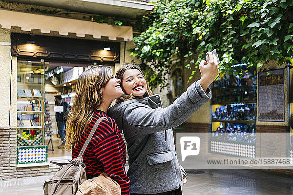 Zwei glückliche junge Frauen  die in der Stadt ein Selfie machen