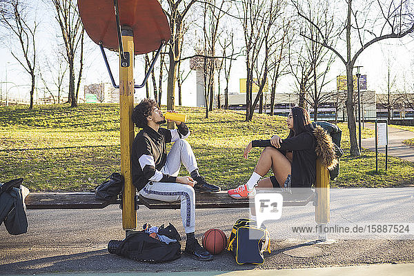 Sportliches junges Paar  das auf einer Bank sitzend eine Pause macht