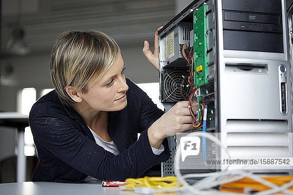 Frau beim Zusammenbau eines Desktop-PCs im Büro