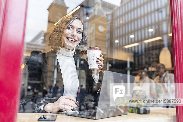 Porträt einer glücklichen Geschäftsfrau mit Laptop in einem Café in der Stadt