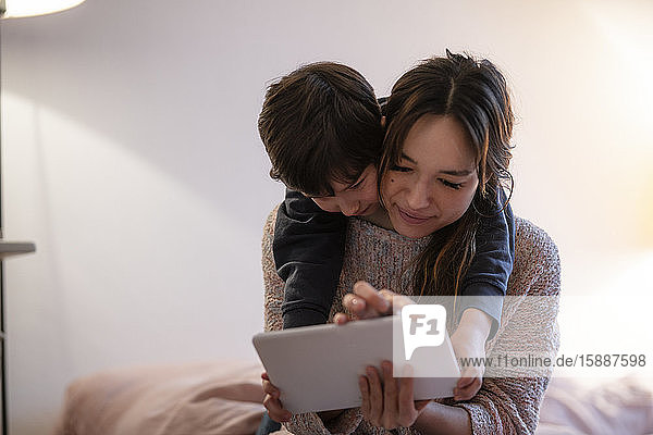Mutter und kleiner Sohn benutzen digitales Tablett zu Hause