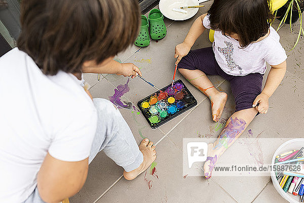 Kleine Mädchen und Jungen malen mit Aquarellfarben