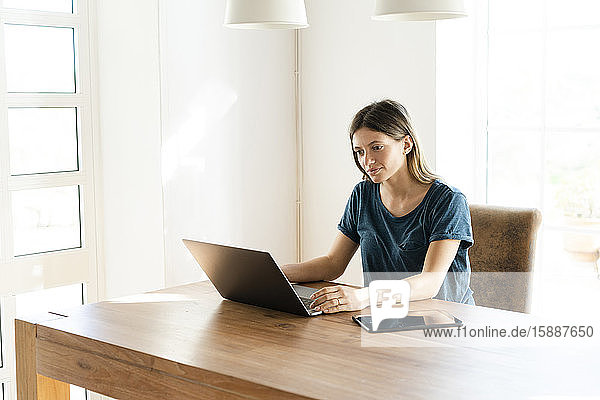 Junge Frau arbeitet zu Hause an ihrem Laptop im Home-Office