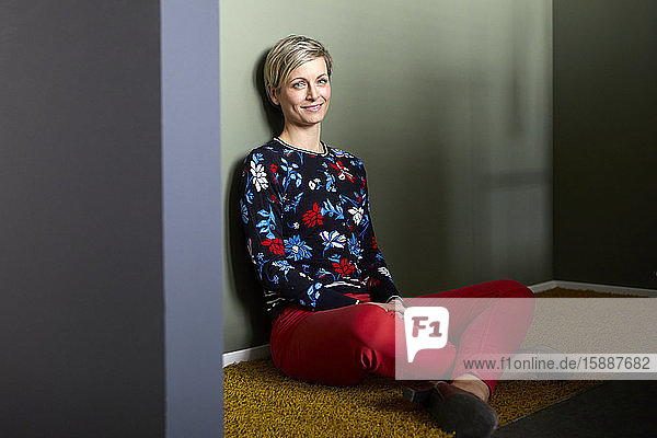 Portrait of a smiling blond woman sitting on carpet