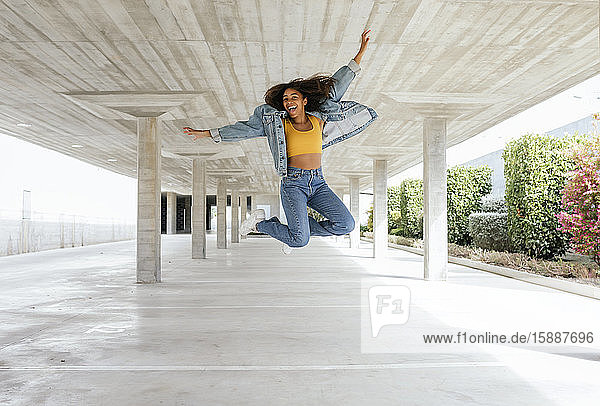 Smiling woman jumping in empty parking deck