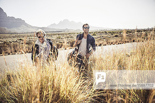 Two men with travelling bag walking on country road