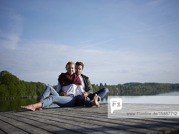 Romantic couple sitting on jetty at the lake