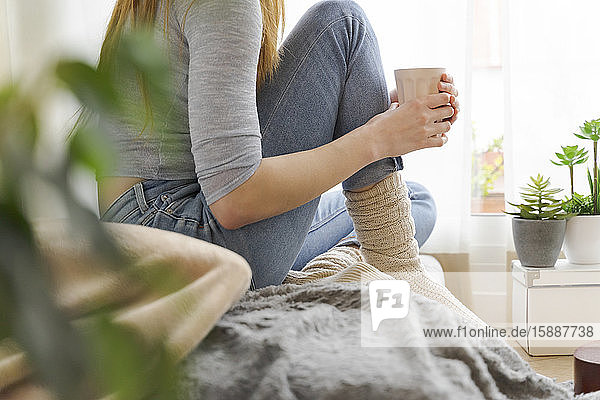 Low section of young woman with coffee mug at home